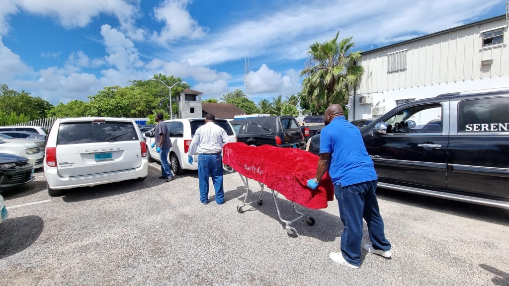 The body of one of the deceased is removed by workers from the morgue in Nassau.