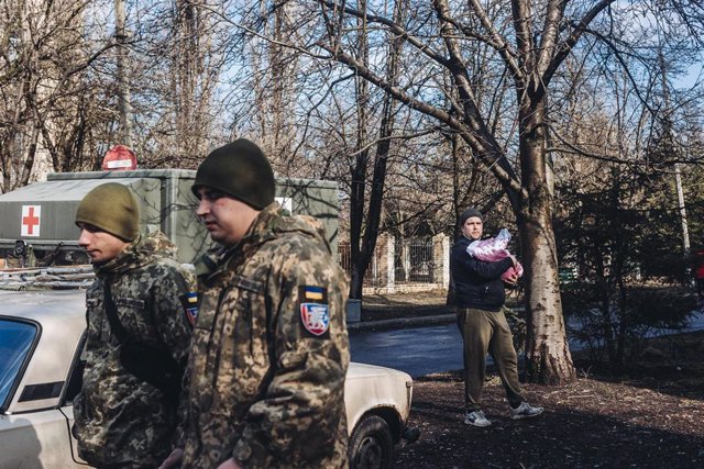 File - Ukrainian army soldiers walk in front of a father and his baby, on February 23, 2022, in Chasiv Yar, Donetsk Oblast, Ukraine.