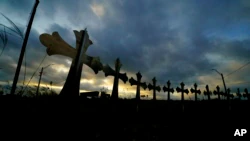 FILE - A truck drives past crosses placed along the highway to honor the victims killed in the recent shooting at Robb Elementary School in Uvalde, Texas, on June 6, 2022.