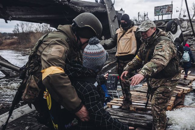 File - Soldiers help a child to cross the river, on March 7, 2022, in Irpin, Ukraine.