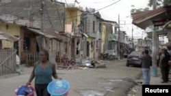 A resident carries her belongings out of the area of ​​an explosion that left others injured and others dead by destroying several houses and vehicles, according to local media, in southern Guayaquil, Ecuador, August 14, 2022. REUTERS/Vicente Gaibor del Pino