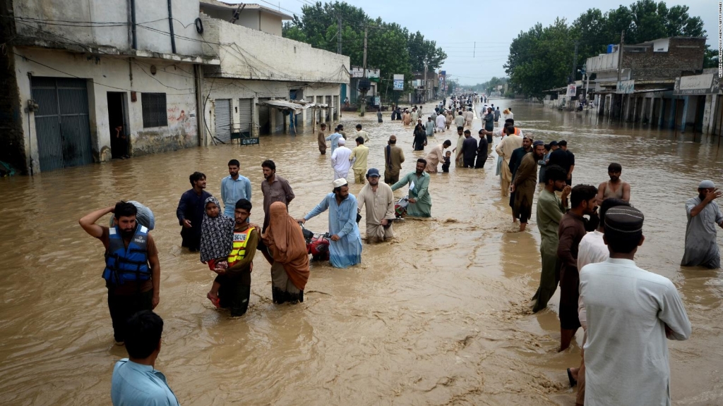 Displaced people walk through a flooded area in Peshawar, Khyber Pakhtunkhwa, Pakistan, on Saturday.