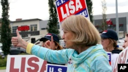 US Senator Lisa Murkowski, R-Alaska, gives a thumbs up to a passing motorist while waving signs, Tuesday, Aug. 16, 2022, in Anchorage, Alaska.