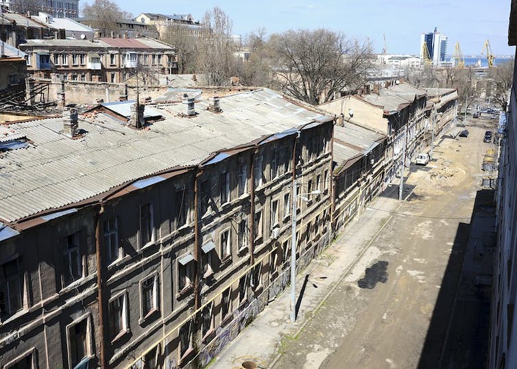 On a sunny day, you see a street of destroyed and bombed-out buildings.