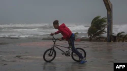 FILE - A young man rides his bicycle on the beach in Nagua, Dominican Republic, on Sept. 19, 2022, as Hurricane Fiona passes through the country.