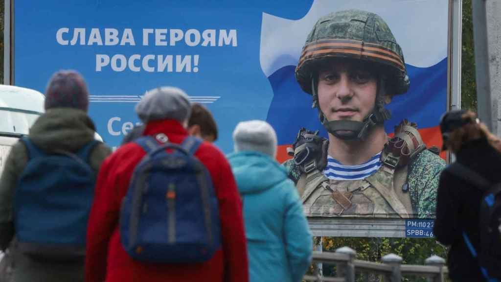 A wartime propaganda poster next to a tram stop in St. Petersburg reads: Glory to the heroes of Russia!