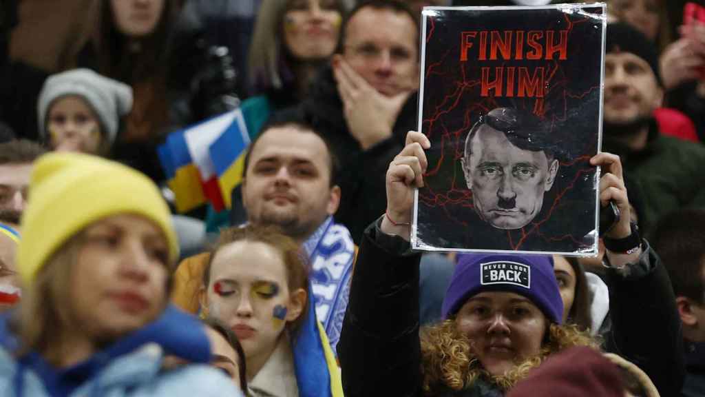 A protester shows a banner where Putin appears dressed as Hitler this Tuesday in Warsaw.