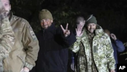 In this image released by the Ukrainian Security Service Press Office, Ukrainian soldiers freed in a Russian-Ukrainian prisoner swap smile near Chernigov, Ukraine, on Wednesday night, September 21, 2022 (Ukrainian Security Service Press Office Security of Ukraine via AP)