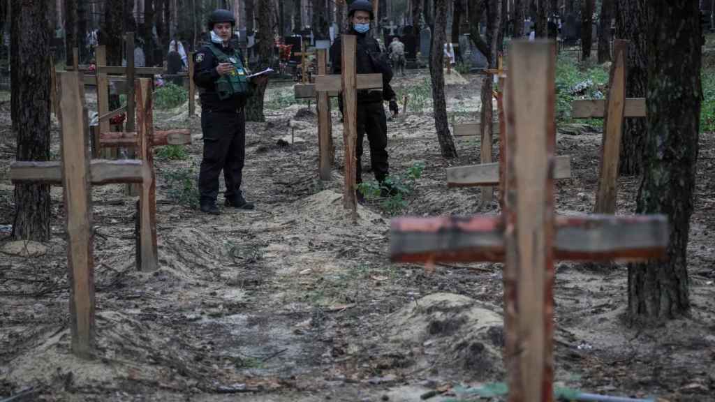 Police work at a mass burial site during an exhumation, as Russia's attack on Ukraine continues, in the city of Izium