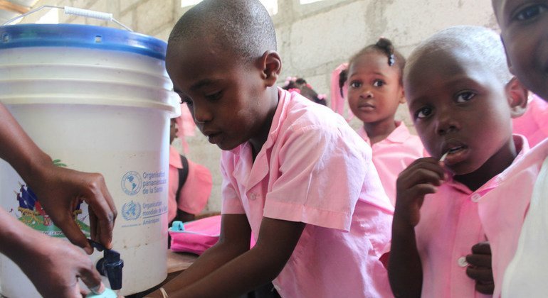 A group of Haitian children learn how to wash their hands properly.