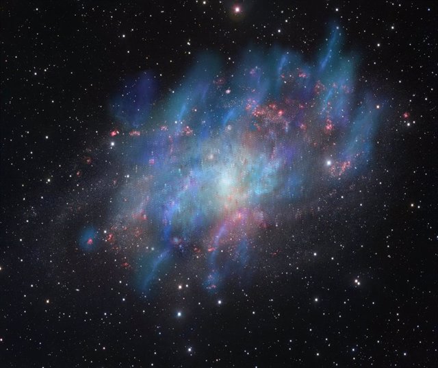 Artist's illustration of cosmic ray-driven winds (blue and green) superimposed on a visible-light image of the Triangulum galaxy M33 (red and white) observed with the VLT Survey Telescope at ESO's Paranal Observatory in Chile.