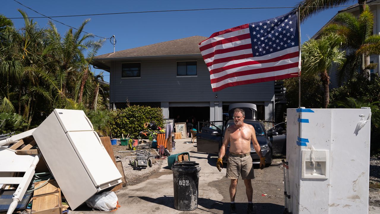 A man stands in front of a home damaged by storm surge in the aftermath of Hurricane Ian in Naples, Florida.