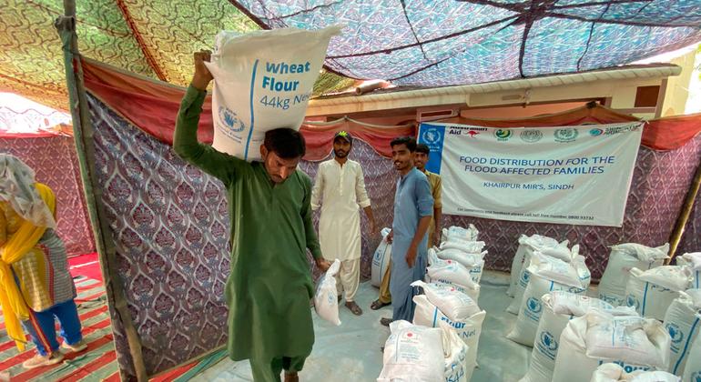 People affected by recent flooding in Pakistan collect flour at a WFP food distribution site.