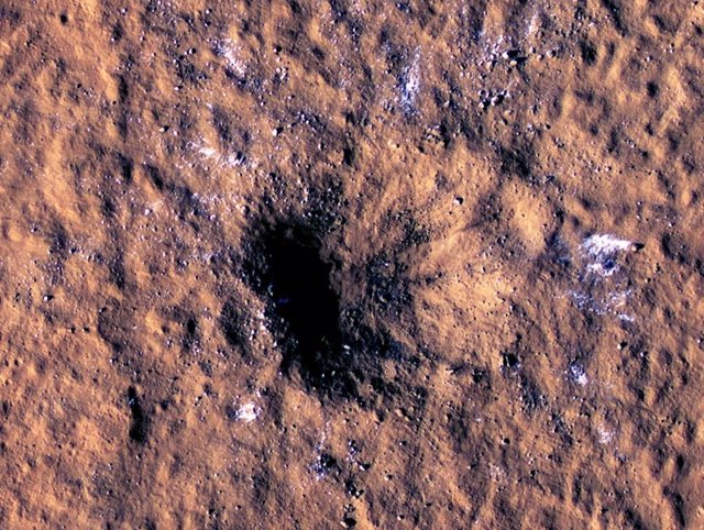 Blocks of rock-sized water ice can be seen around the rim of an impact crater on Mars, as seen by the High Resolution Imaging Science Experiment (HiRISE camera) aboard NASA's Mars Reconnaissance Orbiter.