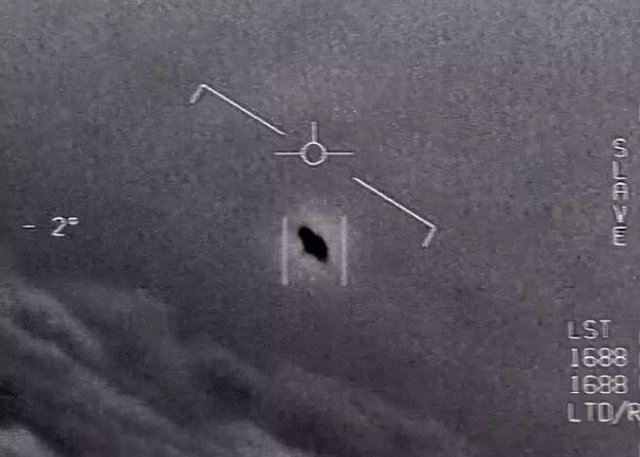 In a video still from 2015, an unexplained object is seen in the center as it rises through the clouds, traveling against the wind. "There's a whole fleet of them"says one US military aviator to another