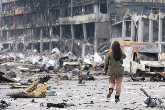 File - A woman takes a picture of a destroyed building in the Ukrainian capital, kyiv