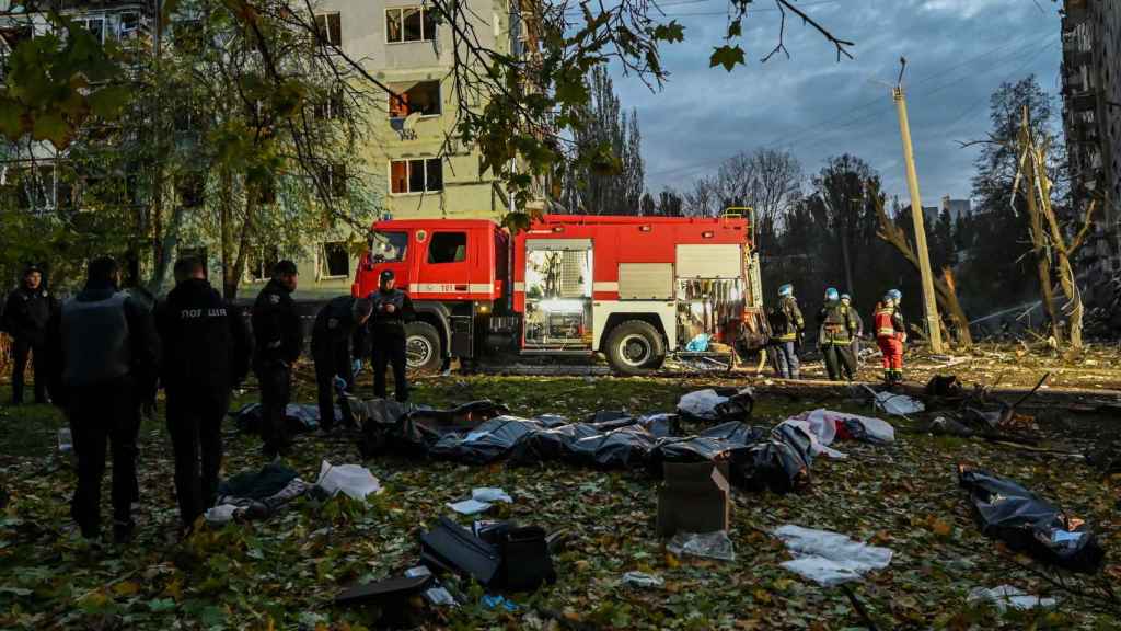 Ukrainian firefighters tend to the wounded after the bombing in Zaporizhia with several dead on the ground.