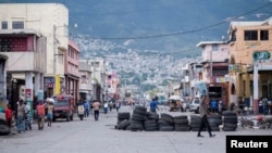 People walk on a quiet street partially blocked with a barricade made of tires, usually full of people and heavy traffic in Port-au-Prince, Haiti, October 13, 2022.