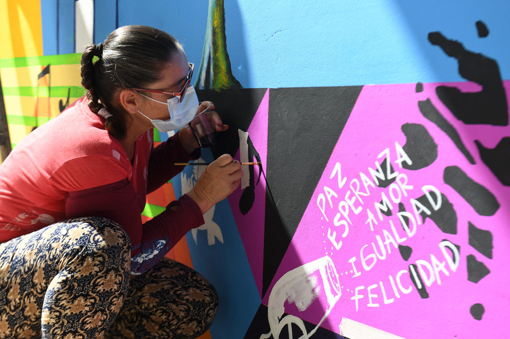 A woman paints a mural for Peace and Reconciliation in Colombia.