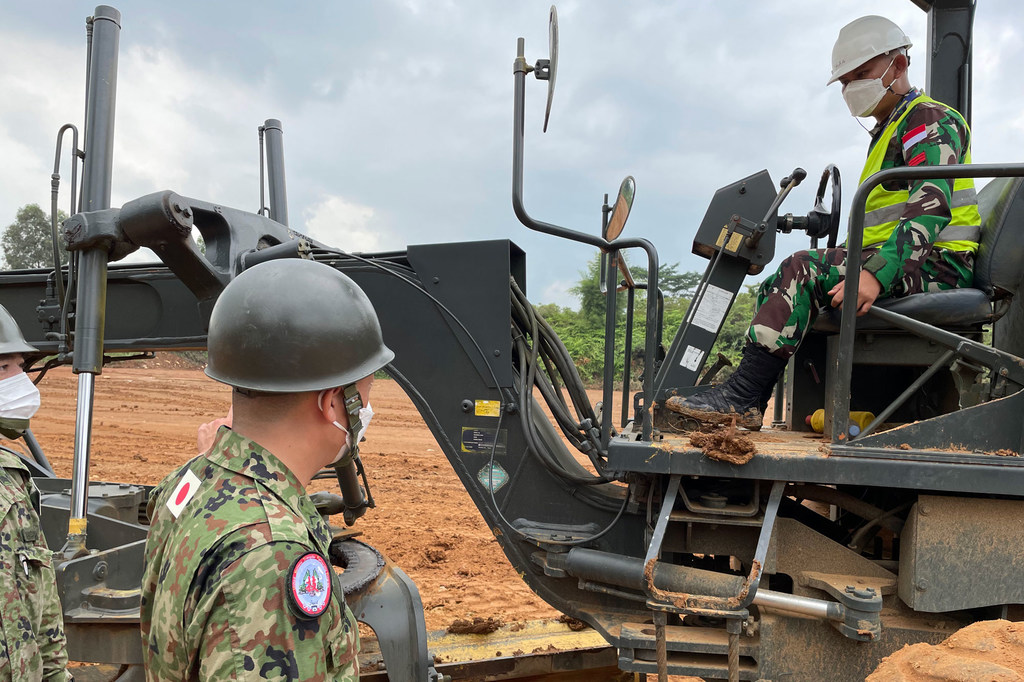 A Japanese military instructor helps a soldier from the Indonesian Army's 3rd Combat Engineering Battalion hone his skills in driving a motor grader, equipment he will need to operate on the mission of maintaining the pa...