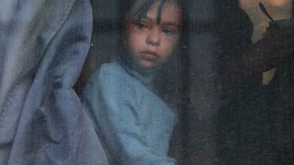 A boy looks out the window of a Kherson deportee bus.