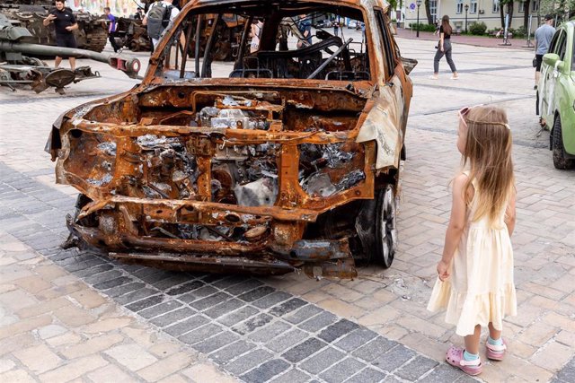 File - Ukrainian girl next to the remains of a vehicle burned in the framework of the war