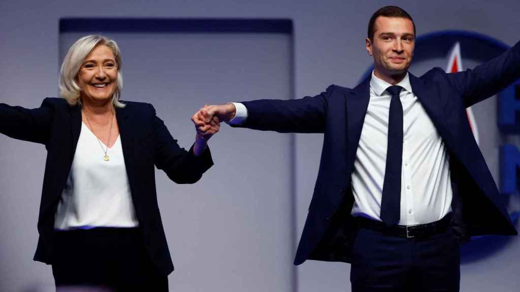 Jordan Bardella, the new president of the far-right National Rally party, holds the hand of his predecessor, Marine Le Pen.