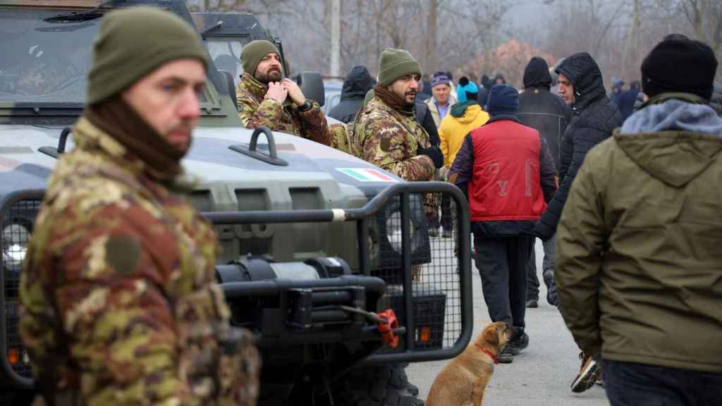 Members of the Italian Armed Forces, part of the NATO peacekeeping mission in Kosovo, watch as local Serbs protest against the government near an obstacle in Rudare.