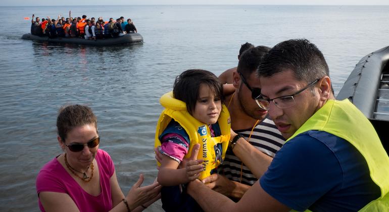 A volunteer helps newly arrived refugees disembark from a large rubber dinghy on the Greek island of Lesbos.  (File photo)