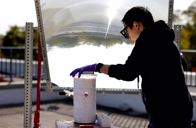 Peng Zhou uses a large lens to focus sunlight onto the catalyst that splits the water.  Outdoors, the device is ten times more effective than the previous ones.