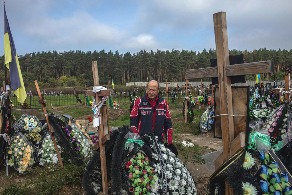 A man mourns his deceased best friend at a cemetery in Bucha, Ukraine.