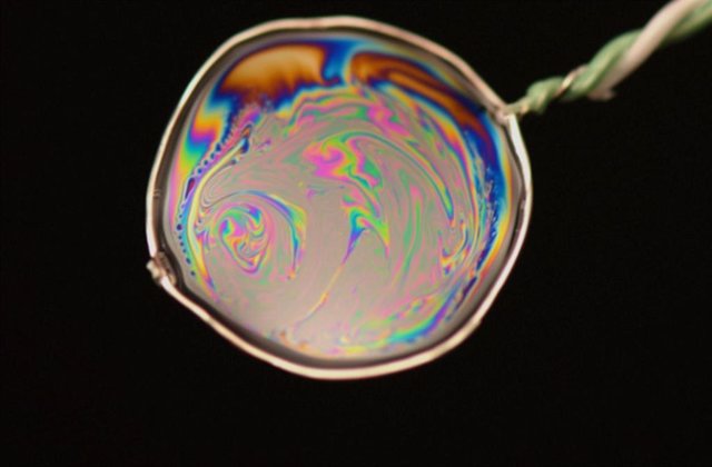 Photograph of a film of soap hanging from a frame made up of a thermocouple probe.