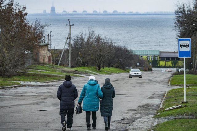 Archive - Several people walk through the town of Nikopol, on the banks of the Dnieper River and with the Zaporizhia nuclear power plant in the background