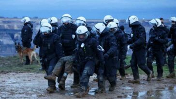 A group of policemen try to evict the protesters, but get stuck in the mud.