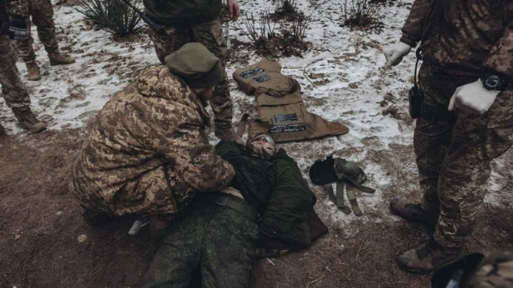 Soldiers from the Wagner Group next to an executed Ukrainian soldier.