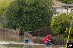 A man and a boy "they navigate" on bicycles through the flooded streets of Watsonville, California, on March 11, 2023.