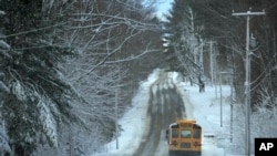 A school bus travels down a slush-covered road as school resumes after a winter storm, Wednesday, March 15, 2023, in Poland, Maine.  The storm dumped heavy, wet snow across parts of the Northeast, leading to tens of thousands of power outages.  (AP Photo/Robert F. Bukaty)