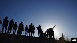 Migrants watch from the Mexican side of the border as others cross the Rio Grande into the United States from Ciudad Juárez, Mexico, Wednesday, March 29, 2023, a day after dozens of migrants died in a fire at a detention center in Mexico City. migrants in Ciudad Juárez.  (AP Photo/Fernando Llano)