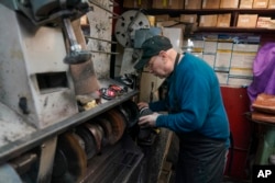 Jairo Cárdenas, owner of Alpha Shoe Repair Corp., polishes a boot he is repairing, on February 3, 2023, in New York.