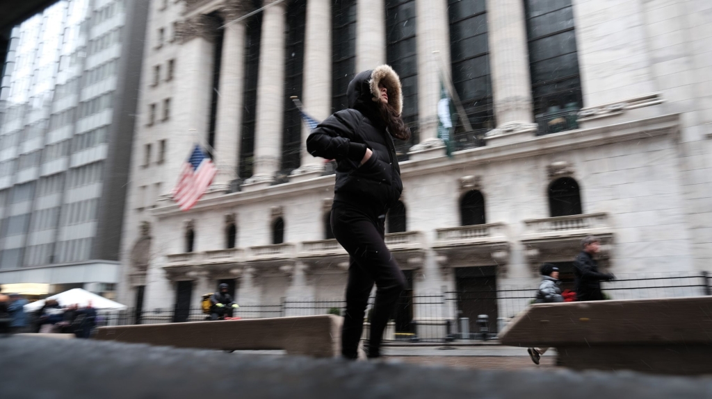 People walk in lower Manhattan next to the New York Stock Exchange (NYSE) under a light snowfall on March 14, 2023 in New York City.  Much of the Northeast is being battered by a late winter storm bringing wind, rain and snow to many areas.  (Credit: Spencer Platt/Getty Images)