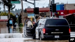 A sheriff's deputy checks his truck as he drives through floodwaters in the community of Pajaro in Monterey County, Calif., Monday, March 13, 2023. (AP Photo/Noah Berger)