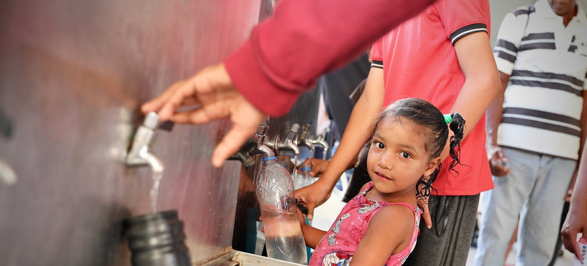 A Venezuelan girl receives drinking water at a temporary housing center.  Photo: IOM/Gema Cortes