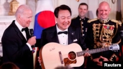 US President Joe Biden presents a guitar signed by artist Don McLean to South Korean President Yoon Suk Yeol at a state dinner, during South Korean President Yoon Suk Yeol's visit, at the White House in Washington, U.S., April 26, 2023. REUTERS/Evelyn Hockstein