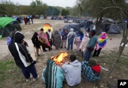 FILE - Migrants endure cold weather around a campfire at a makeshift camp on the US-Mexico border on December 23, 2022 in Matamoros, Mexico.