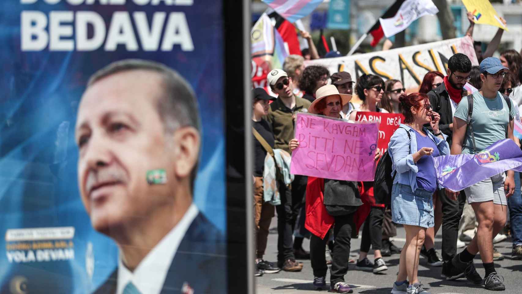 People hold banners near a picture of Turkish President Recep Tayyip Erdogan, during a May Day celebration rally