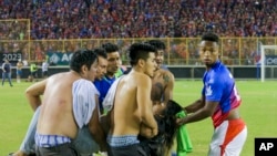 A group of fans carry an injured man towards the field of the Cuscatlán stadium in San Salvador on Saturday, May 20, 2023.