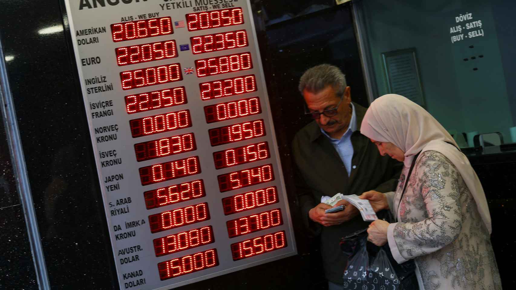 Several people visit a currency exchange office this Monday.