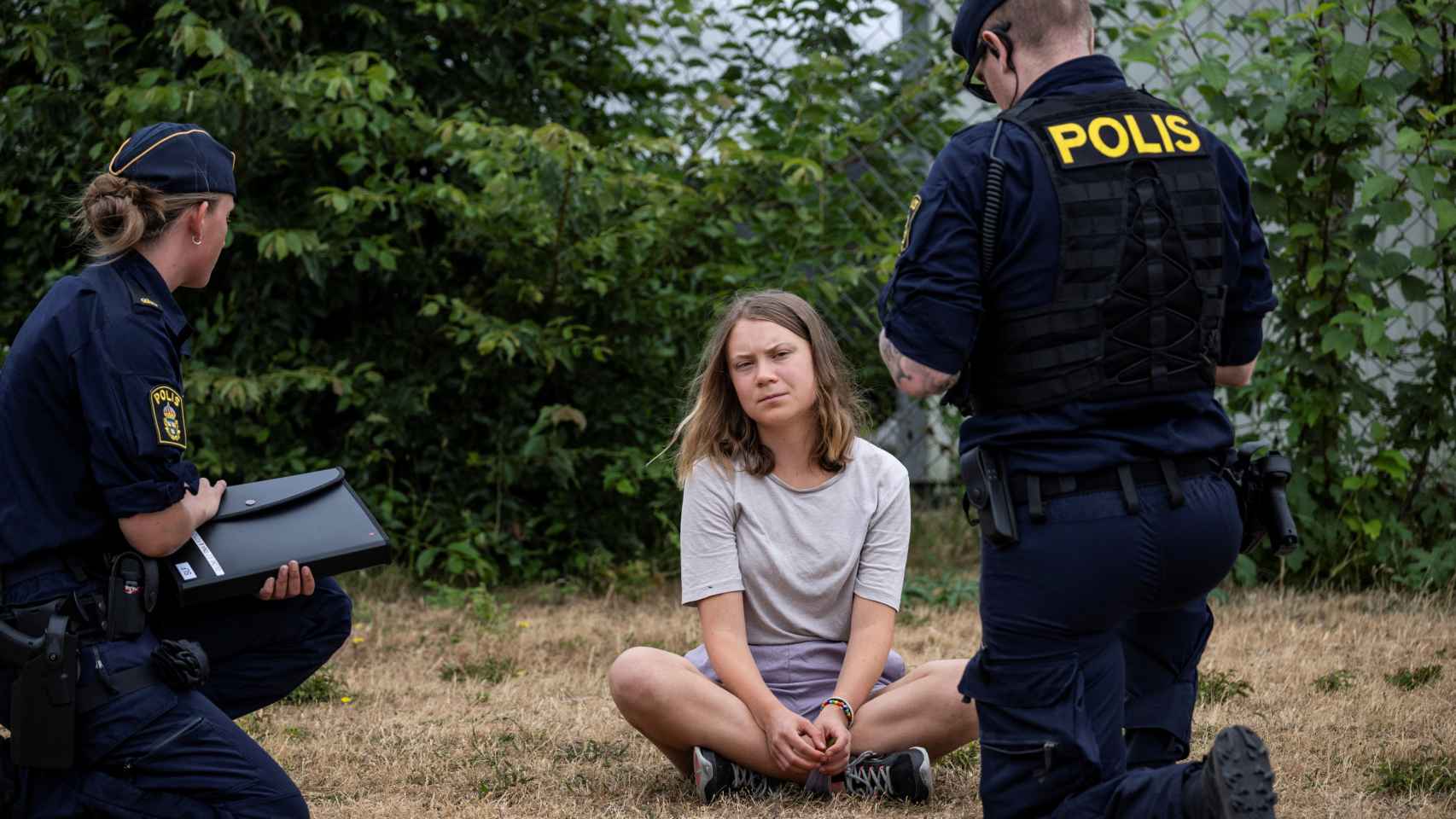 Two Swedish police officers talk to Greta Thunberg.