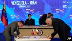 With Iranian President Ebrahim Raisi and Venezuelan President Nicolás Maduro seated in the background, the oil ministers of both countries, Venezuelan Pedro Rafael Tellechea, left, and Iranian Javad Owji, sign an agreement at the Miraflores presidential palace in Caracas, Venezuela, on Monday, June 12.  , 2023.