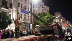 Members of the Wagner Group military company load their tank onto a truck on a street in Rostov-on-Don, Russia, Saturday, June 24, 2023, before leaving an area at the Southern Military District headquarters.